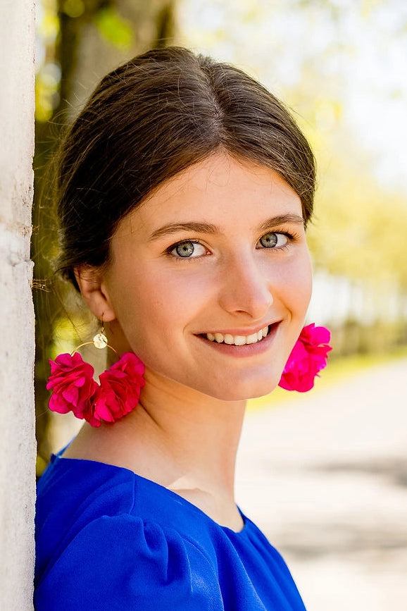 Jeune femme portant des boucles d'oreilles en forme de créoles avec des fleurs d'hortensia stabilisées de couleur fuchsia. Créé par Bellemond.