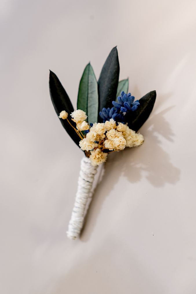 Boutonnière composée de lavande, de feuilles d'olivier et de gypsophile stabilisé. Créé par Bellemond.