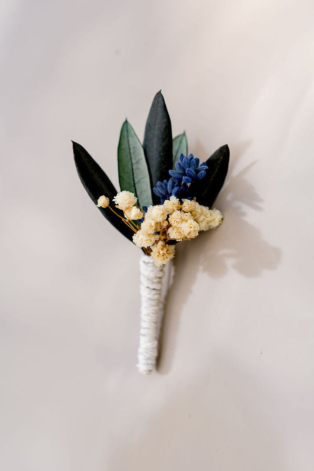 Boutonnière composée de lavande, de gypsophile et de feuilles d'olivier stabilisé. Créé par Bellemond.
