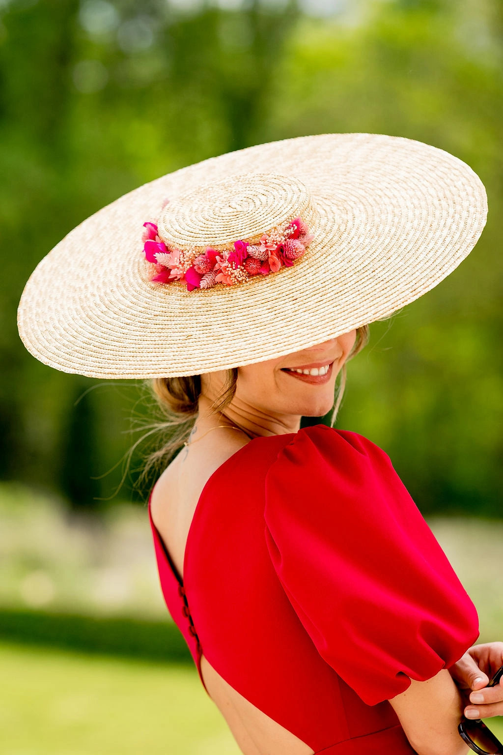 Jeune femme portant une capeline en paille naturelle surmonté autour de la moitié de la couronne de fleurs séchées et stabilisées roses, corails, et fuchsia. Créé par Bellemond.
