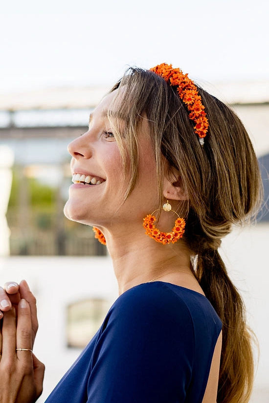 Jeune femme portant des boucles d'oreilles en fleurs séchées glixia oranges. Créé par Bellemond.