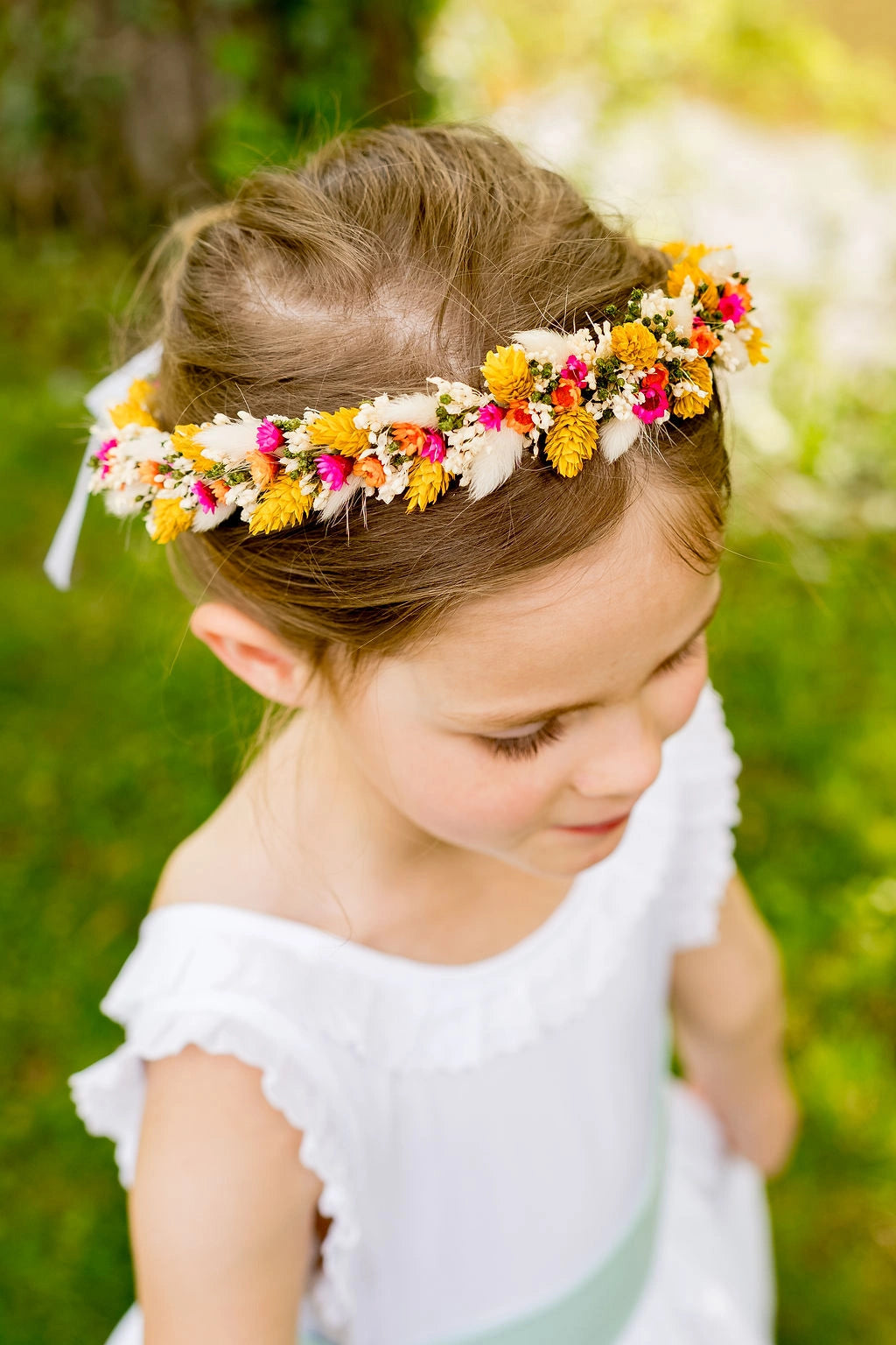 Petite fille portant une couronne de fleurs séchées multicolore sur la tête. Créé par Bellemond.