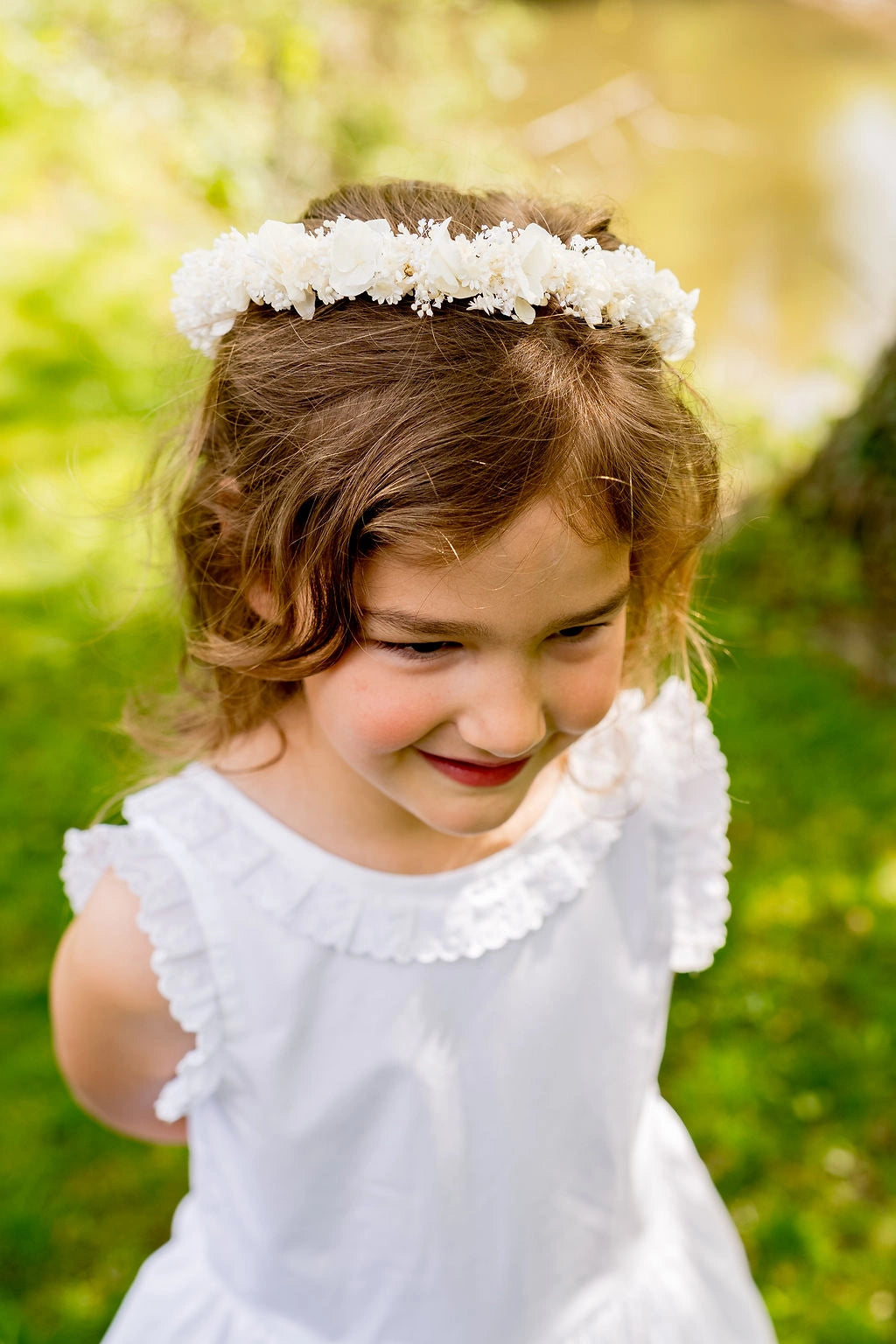 Petite fille habillée de blanc avec dans ses cheveux une couronne de fleurs séchées et stabilisées blanc. Créé par Bellemond.
