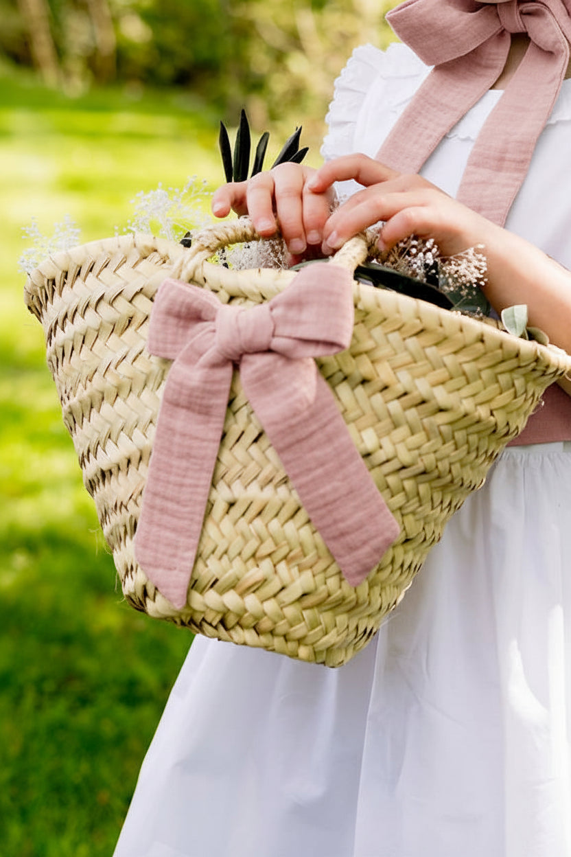 Petit panier avec noeud barrette de couleur vieux rose dans les mains d'un jeune enfant pour un cortège. Créé par Bellemond.