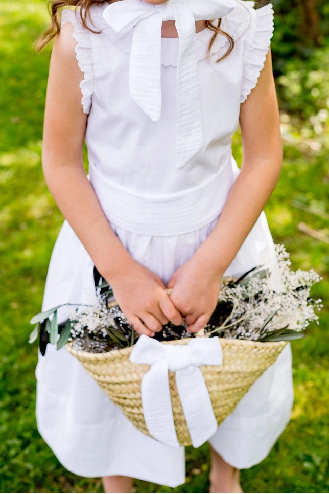 Panier de cortège en feuille de palmier avec un petit noeud blanc en gaze de coton. Tenu à la main par un enfant de cortège. Créé par Bellemond.