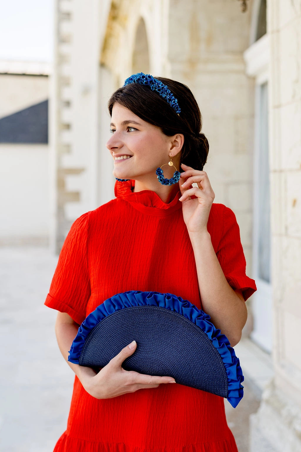Jeune femme habillée d'orange portant une pochette bleue marine en forme de demie lune avec des fronces. Créé par Bellemond.