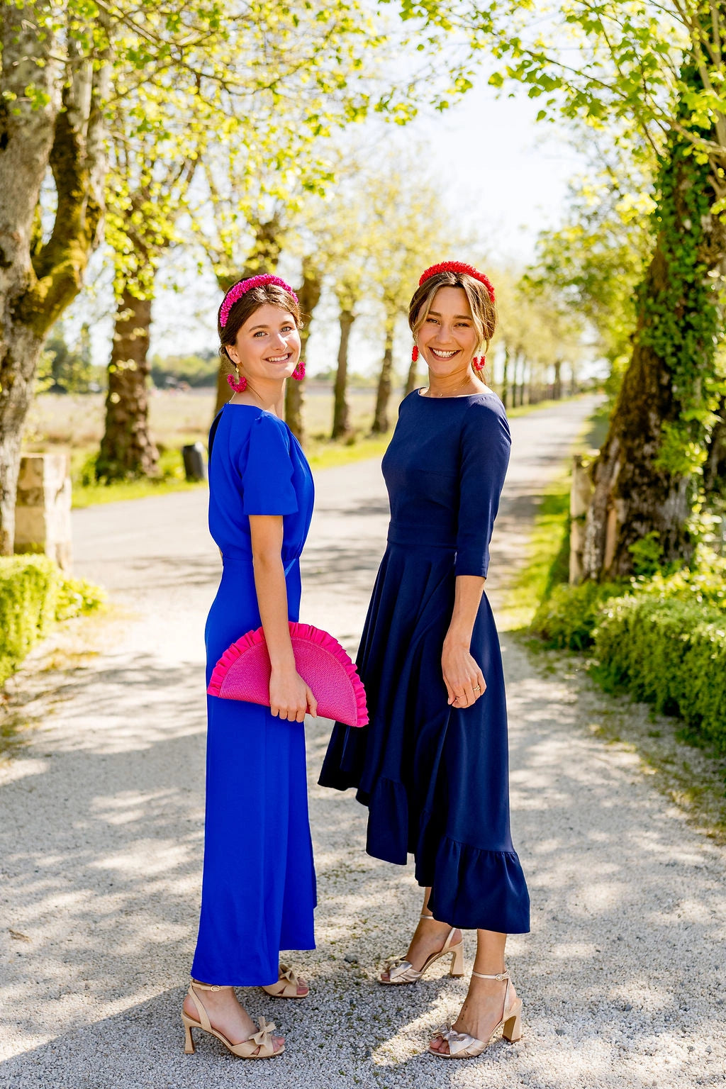 Deux jeunes femmes en tenue chic dont l'une d'entre elles porte une pochette rose fuchsia avec des fronces. Créé par Bellemond.