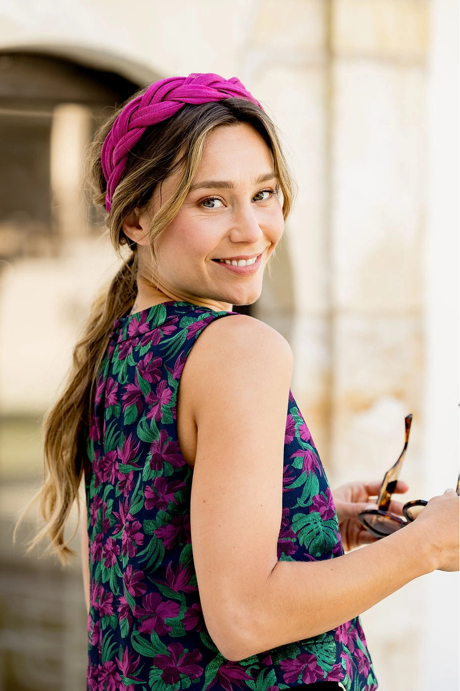 Jeune femme habillée d'un top multicolore ayant dans les cheveux un serre-tête tressé en sinamay de couleur bougainvillier. Créé par Bellemond.