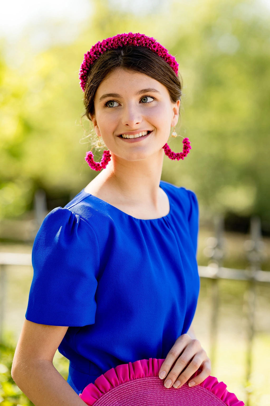 Jeune femme portant une robe bleue roi et un serre-tête composé de glixia fuchsia. Créé par Bellemond.