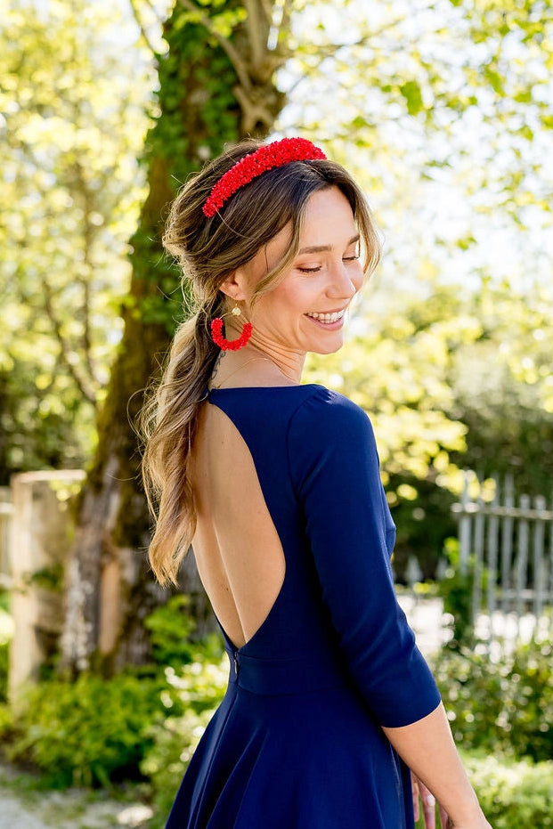 Jeune femme portant une robe bleue marine avec dans les cheveux un serre-tête composé de glixia rouges. Créé par Bellemond.