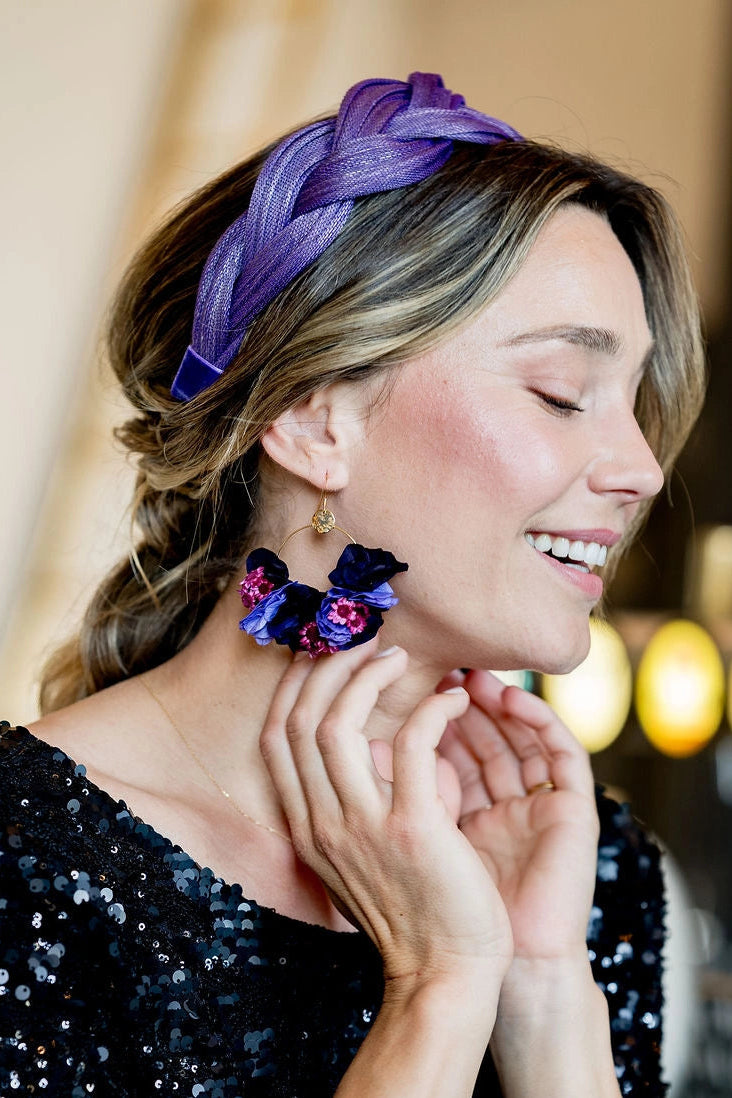 Jeune femme portant des boucles d'oreilles dans les tons violet et lila composé de fleurs séchées et stabilisées notamment de l'hortensia. Créé par Bellemond. 