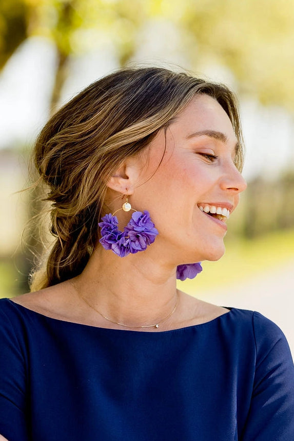 Jeune femme portant des boucles d'oreilles en fleurs d'hortensia stabilisées de couleur mauve et montés sur créoles. Créé par Bellemond.