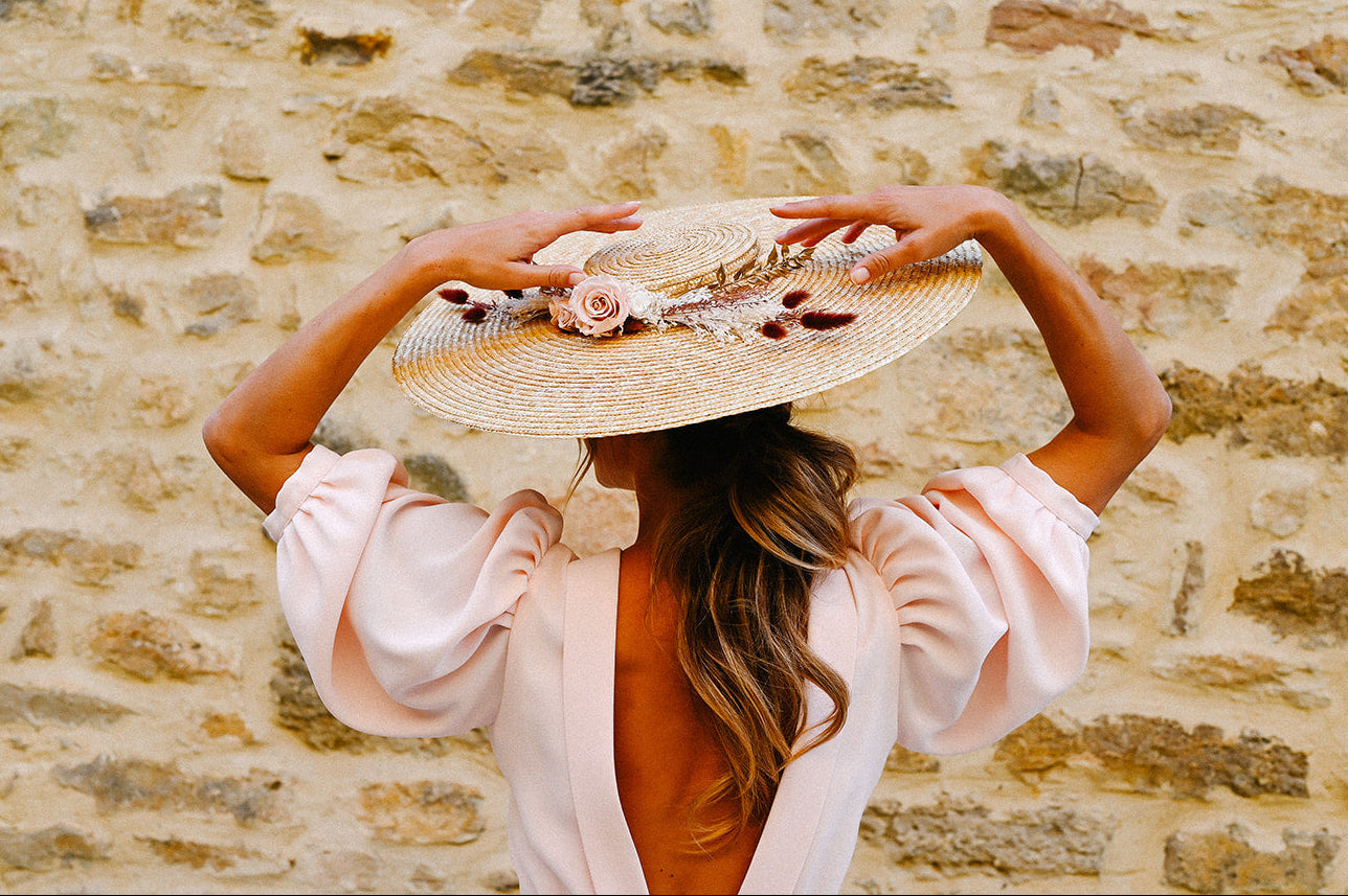 Chapeau Gloria surmonté de fleurs dans les tons roses et dorés créé par Bellemond.