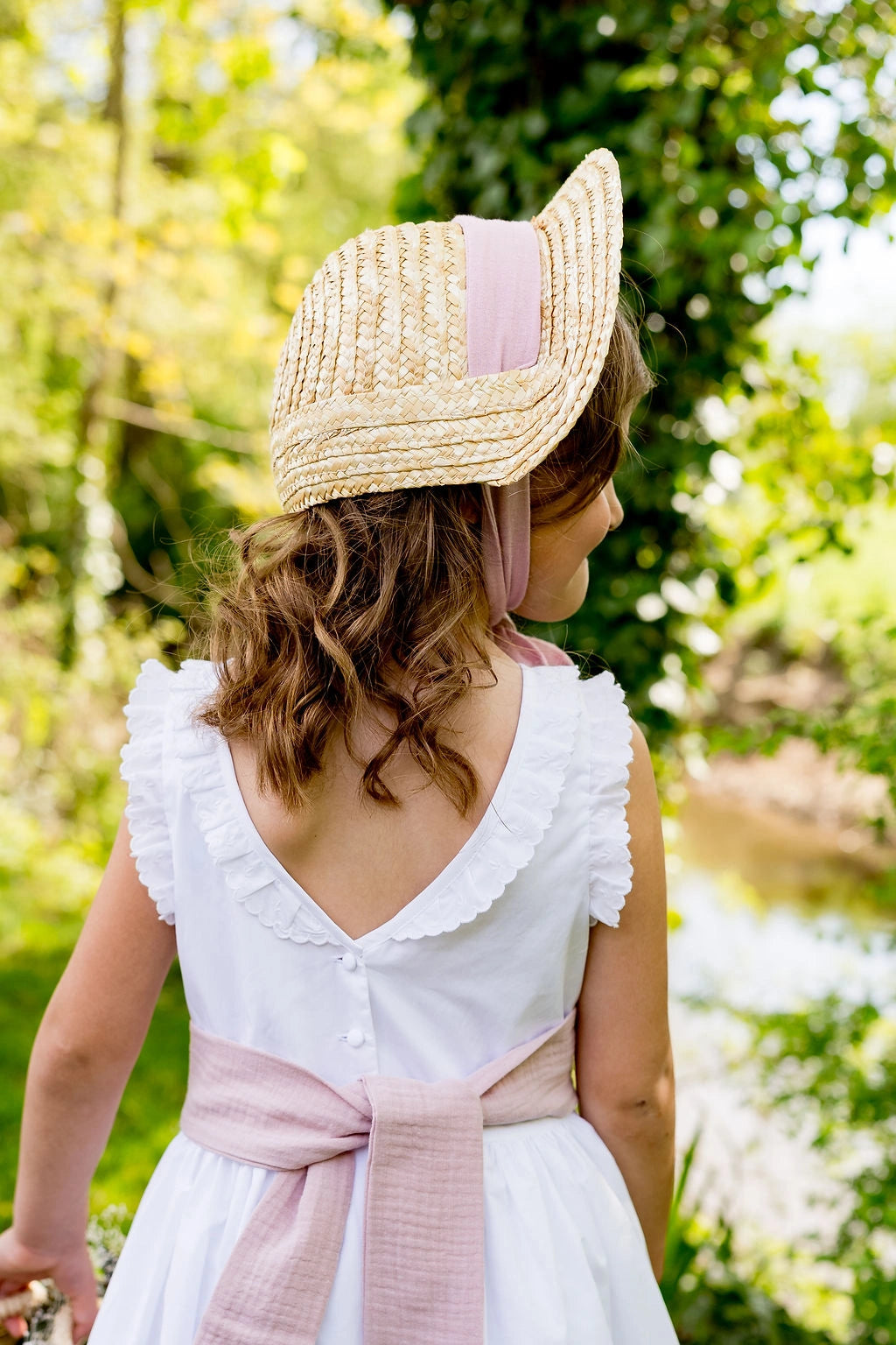 Petite fille portant un petit chapeau de paille de type creusois avec un ruban en coton de couleur vieux rose. Créé par Bellemond.