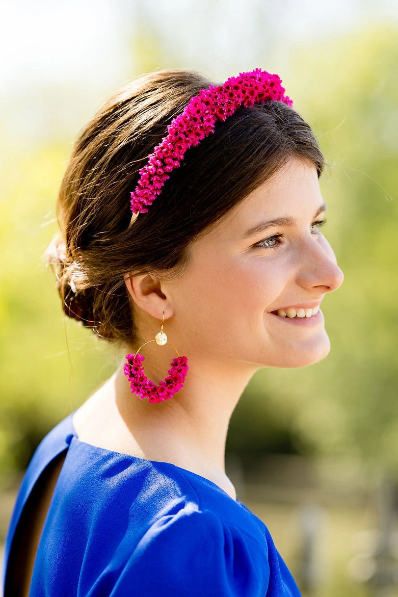 Jeune femme portant des boucles d'oreilles en fleurs séchées glixia fuchsia. Créé par Bellemond.