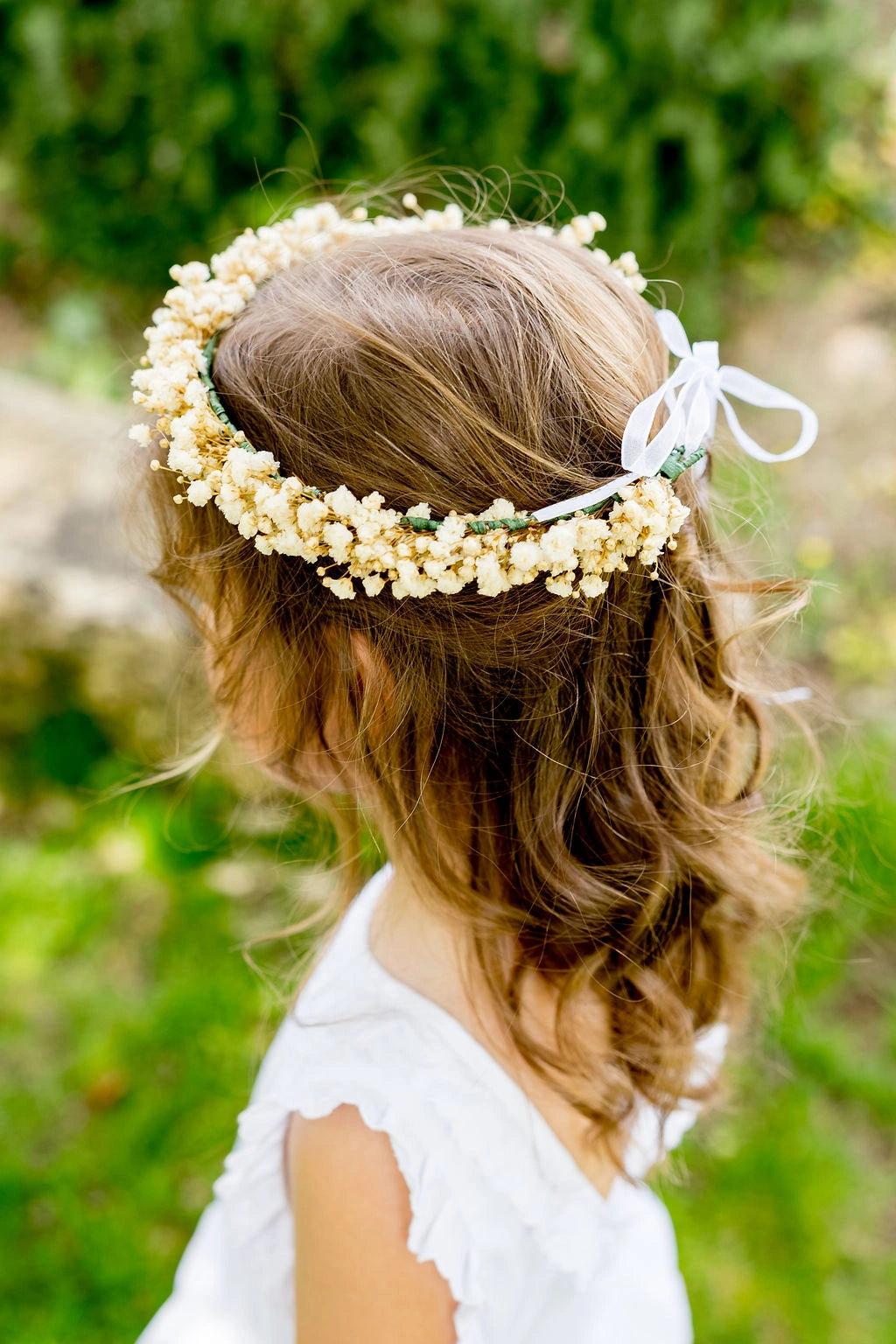 Petite fille de dos avec cheveux lâchés portant une couronne de gypsophile stabilisé sur la tête. Créé par Bellemond. 