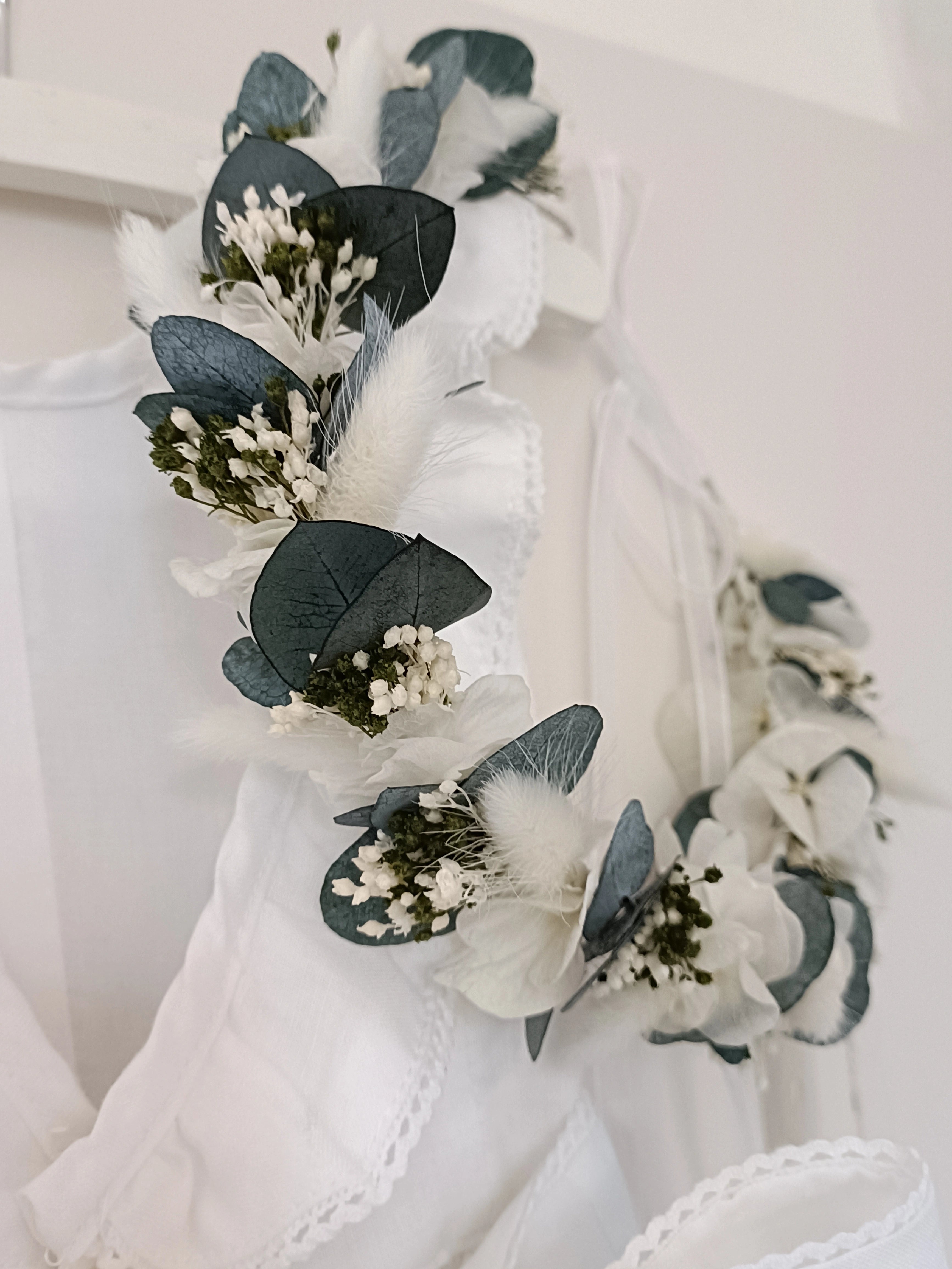 Zoom sur une couronne de fleurs séchées et stabilisées de couleur verte et blanche. Créé par Bellemond. 