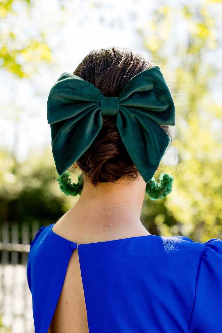 Jeune femme de dos dans une robe bleue roi avec dans les cheveux un noeud de type barrette en tissu velours vert sapin. Créé par Bellemond. 