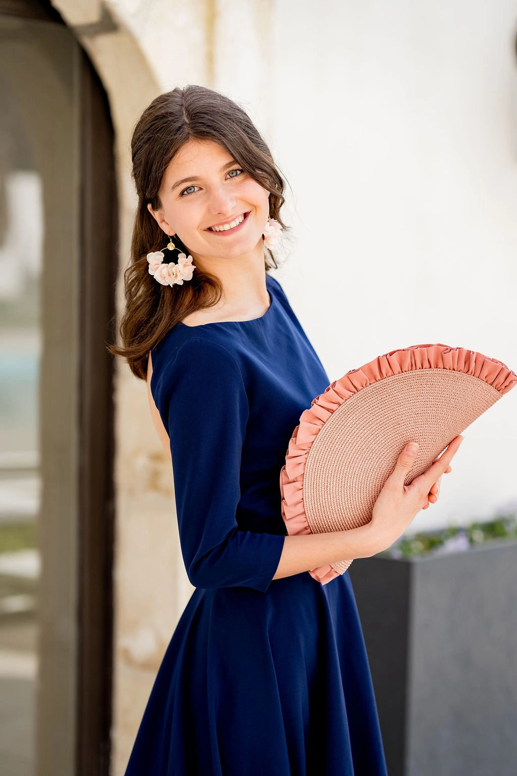 Jeune femme habillée en bleu marine portant une pochette en demie lune de couleur vieux rose dont dépassent des volants. Créé par Bellemond.
