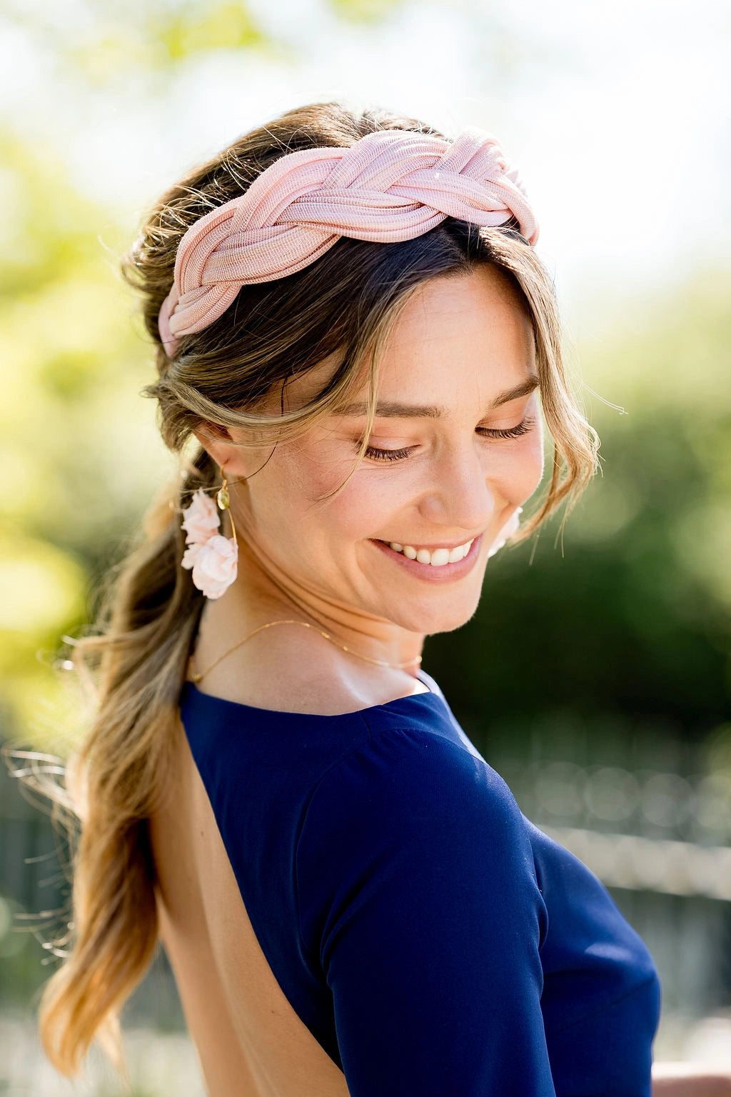 Jeune femme avec robe bleue portant un serre-tête tressé en sinamay de couleur rose pâle avec des boucles d'oreilles de la même couleur. Créé par Bellemond.