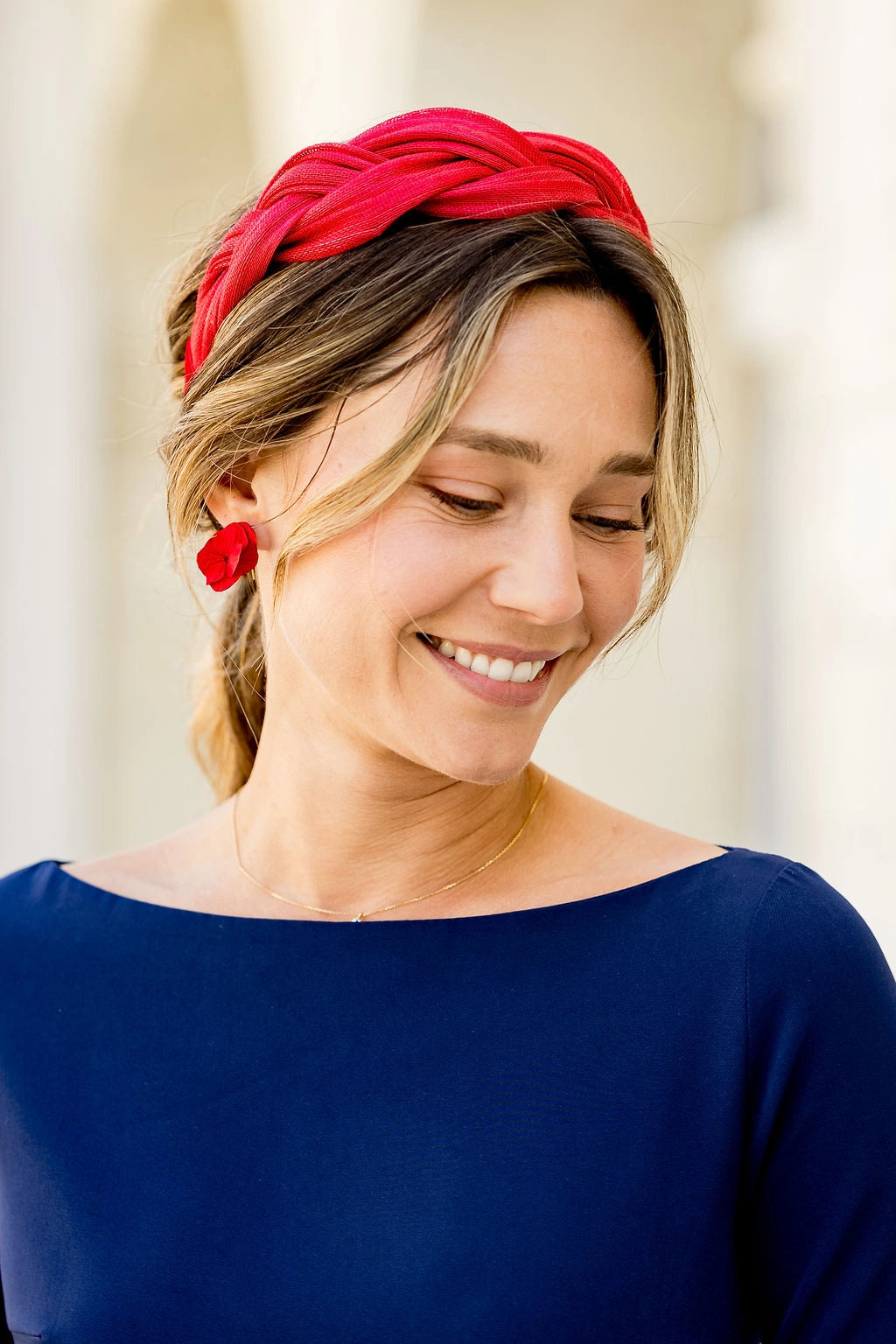 Jeune femme habillée de bleu portant un serre-tête tressé rouge en sinamay. Créé par Bellemond.